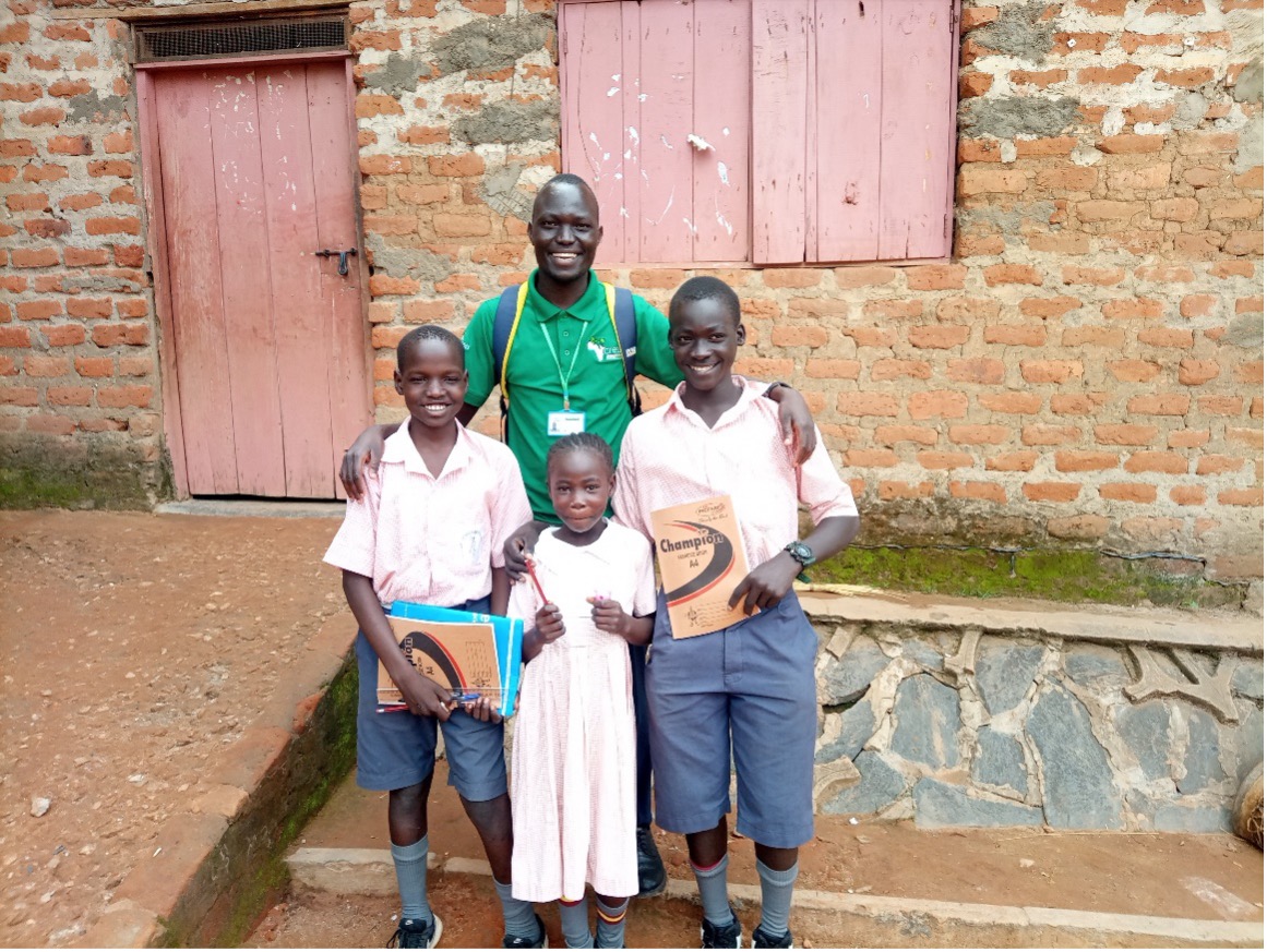 children in pink uniform smiling with adult in green uniform