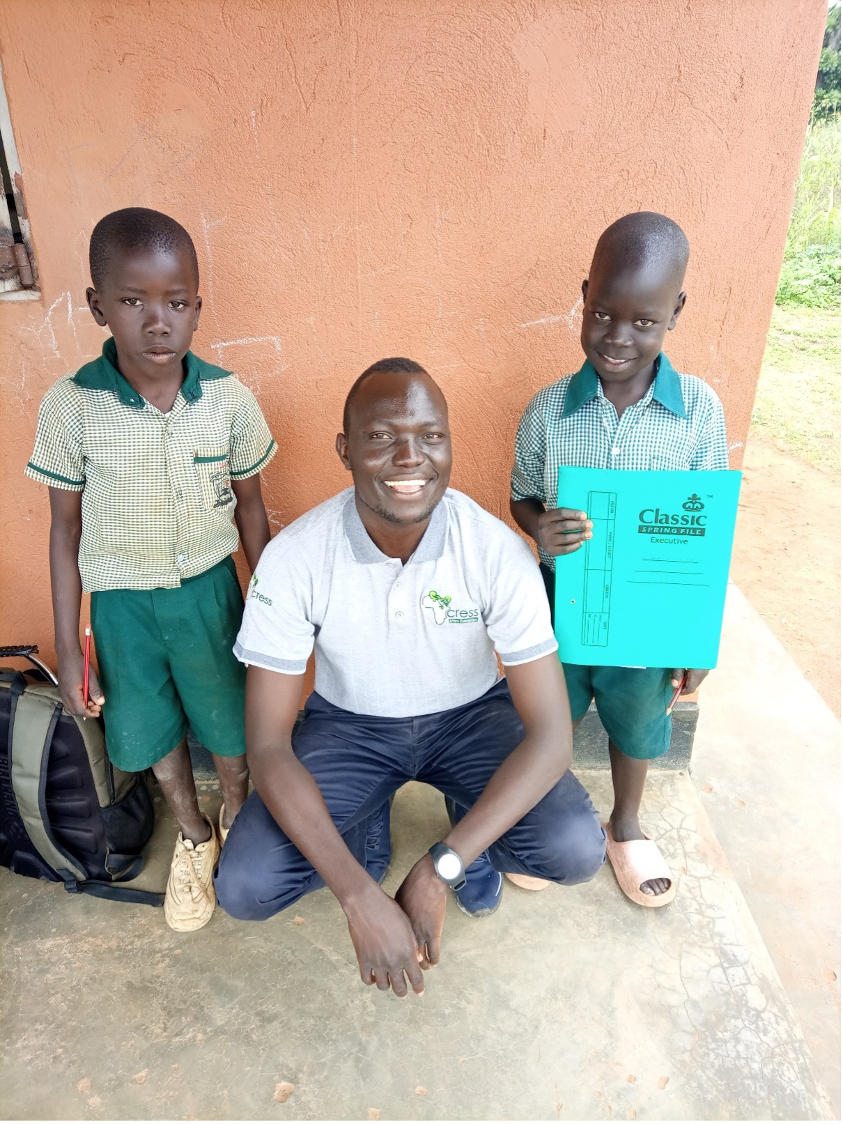 two young children in green uniform with adult crouched between them