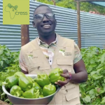 Man smiling in khaki top. Holding bowl of green peppers