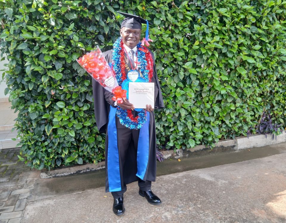Man in cap and gown holding flowers and certificate, smiling