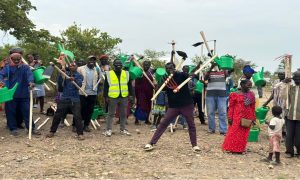 group smiling at camera holding up gardening equipment