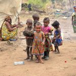 group of children facing camera, smiling. Wearing patterned dresses.