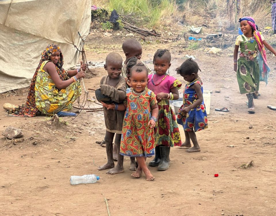 group of children facing camera, smiling. Wearing patterned dresses.