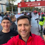 two men smiling. under red marathon banner.