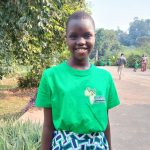 Girl in bright green tshirt, with yellow Africa logo and green patterned skirt.