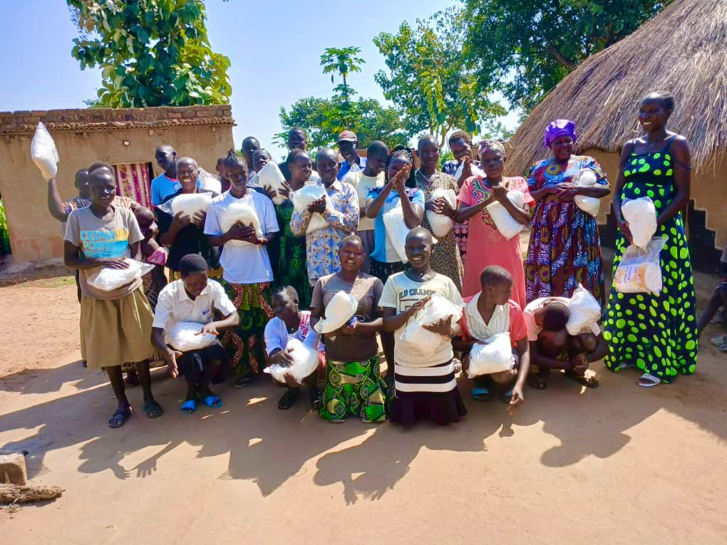 a crowd of women standing together, smiling. They are all holding white mosquito nets